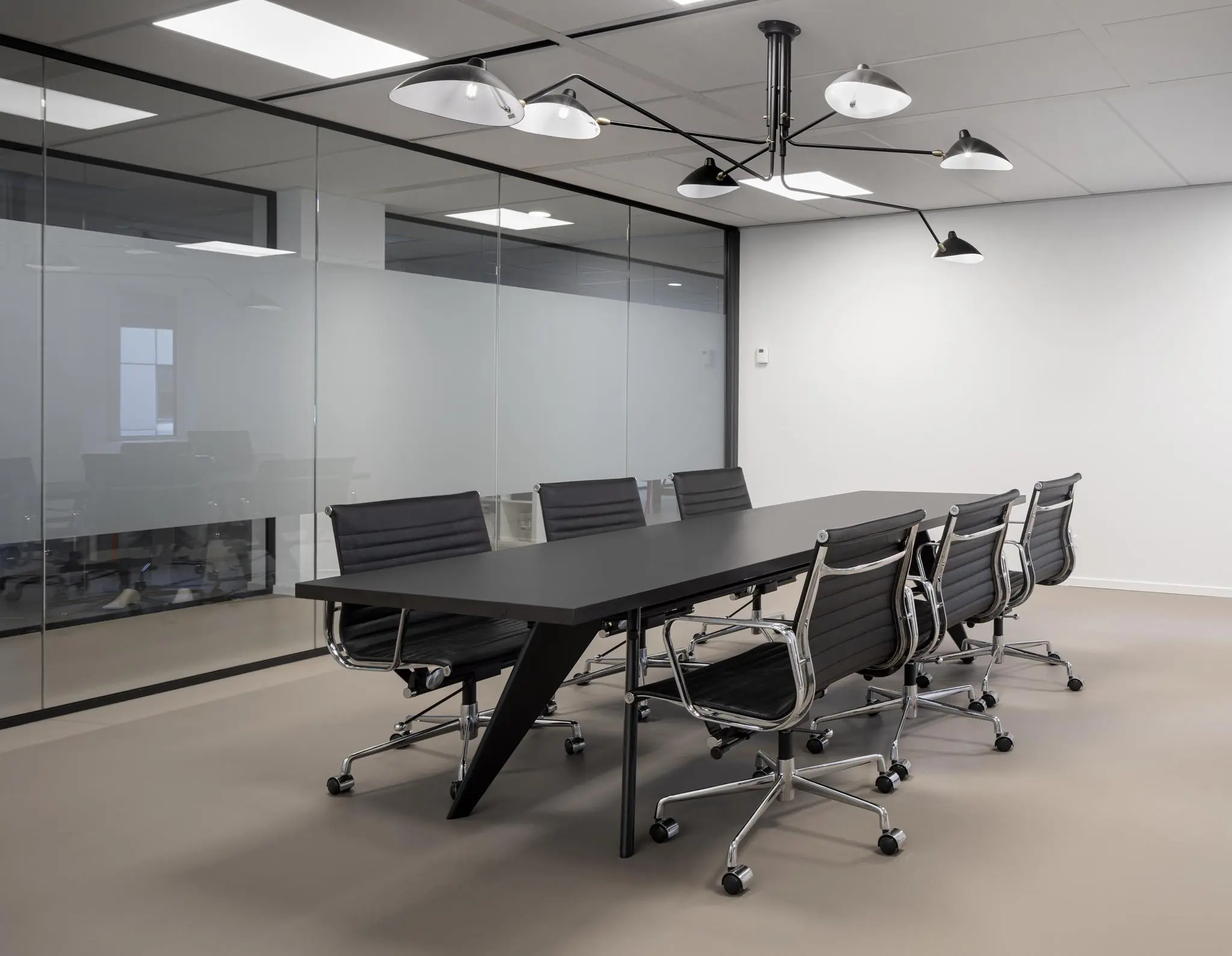 Moderne vergaderruimte aan de Van Boshuizenstraat met zwart conferentietafel, acht zwarte bureaustoelen en glazen wanden.